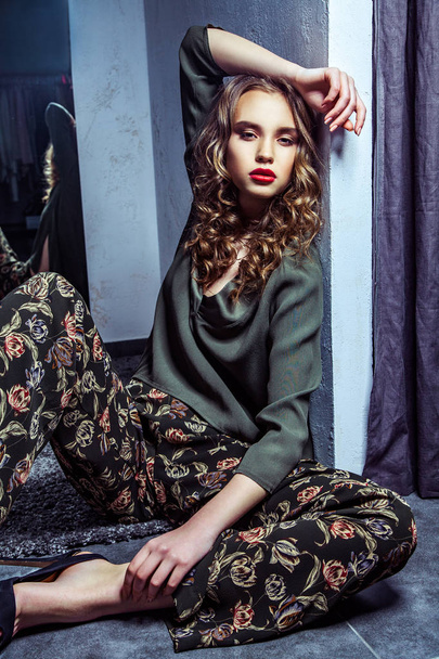 Fashion model with makeup and wavy hairstyle sitting on floor in fitting room  - Fotografie, Obrázek