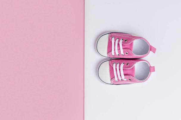 Cute pink baby girl sneakers close up on pink and white background - Foto, Imagem