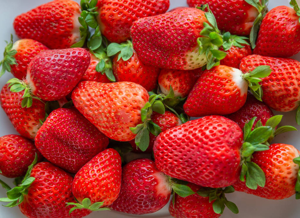 Blick von oben auf eine Reihe reifer Erdbeeren unterschiedlicher Größe - Foto, Bild