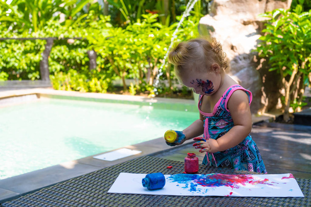 kislány festékek ujjfestékekkel a medence mellett. - Fotó, kép