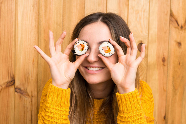 Young woman with sushi over wood background - Photo, Image
