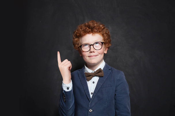 Child boy looking up and pointing on chalkboard background - 写真・画像