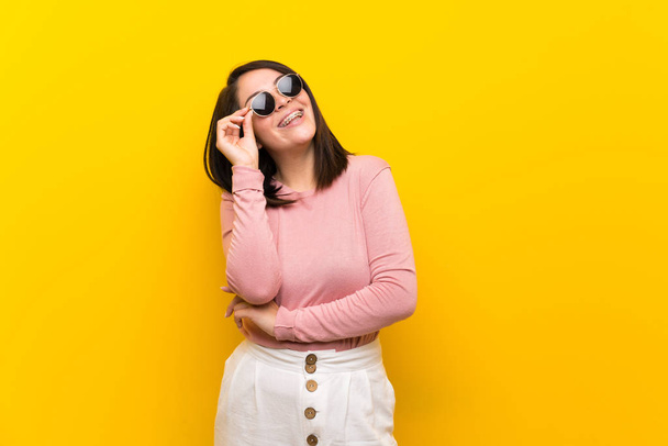 Young Mexican woman over isolated yellow background with glasses and happy - Fotografie, Obrázek