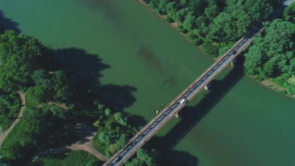 4K antena z góry na dół samochodów brakuje sobie nawzajem, jazdy wzdłuż długiego mostu, nad spokojną zieloną rzekę wody. 4K. - Materiał filmowy, wideo