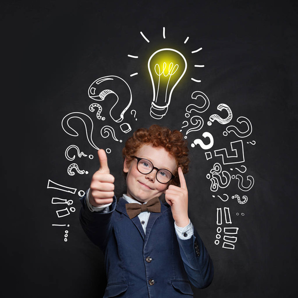 Smart kid student and lightbulb on blackboard background.  - Photo, Image