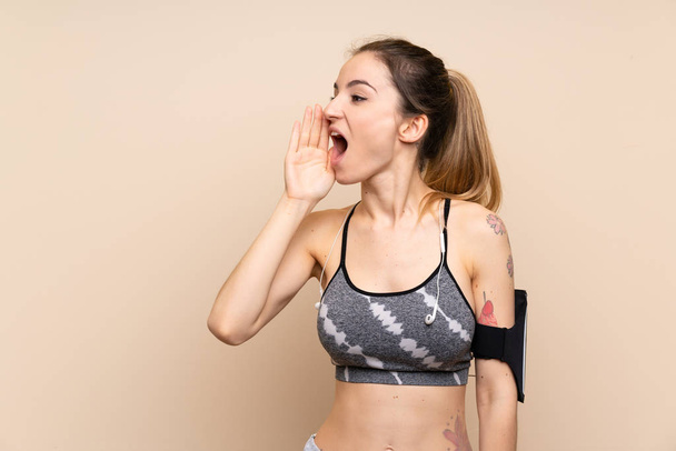 jong sport vrouw over geïsoleerde achtergrond schreeuwen met mond wijd open - Foto, afbeelding