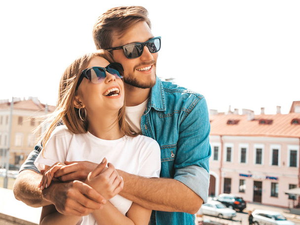 Portrait of smiling beautiful girl and her handsome boyfriend. Woman in casual summer jeans clothes. Happy cheerful family. Female having fun on the street background in sunglasses - Fotó, kép