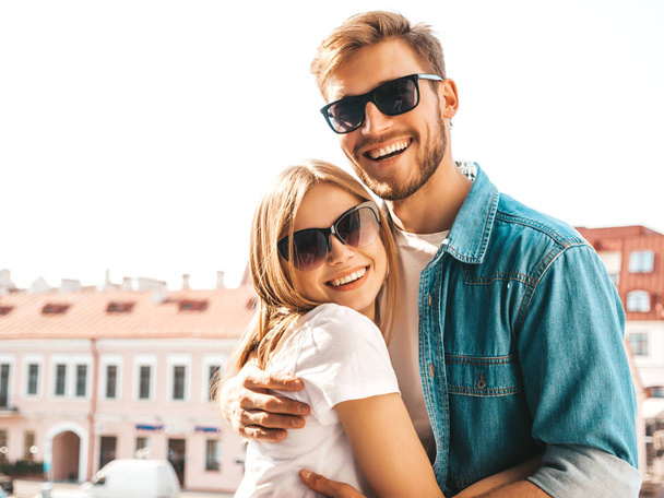 Portrait of smiling beautiful girl and her handsome boyfriend. Woman in casual summer jeans clothes. Happy cheerful family. Female having fun on the street background in sunglasses - Foto, Bild