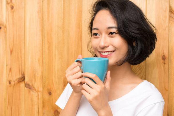 Asian young woman having breakfast holding a cup of coffee - Photo, Image