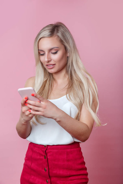 beautiful woman chatting by mobile phone over pink background - Фото, изображение