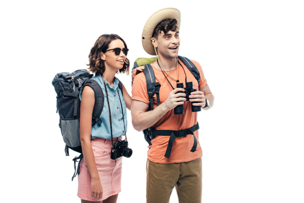 two young tourists with binoculars and digital camera looking away and smiling isolated on white - Foto, imagen