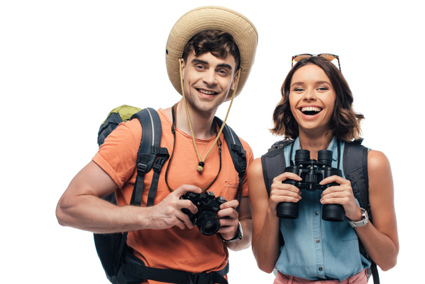 zwei glückliche junge Touristen mit Digitalkamera und Fernglas, die isoliert auf weiß in die Kamera lächeln - Foto, Bild