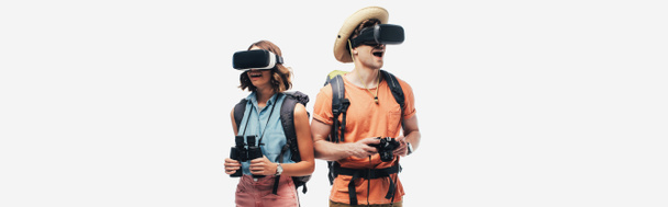 panoramiczne ujęcie dwóch młodych turystów z lornetką i aparatem cyfrowym za pomocą zestawów słuchawkowych rzeczywistości wirtualnej na szarym tle - Zdjęcie, obraz