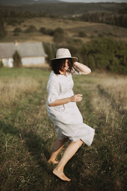 Stylish girl in linen dress running barefoot among herbs and wil - Photo, image
