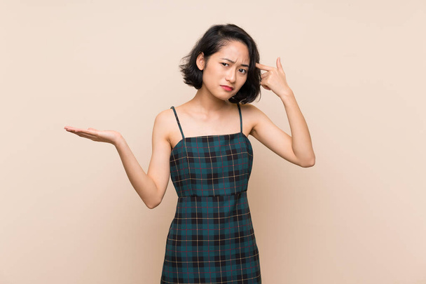Asian young woman over isolated yellow wall making the gesture of madness putting finger on the head - Photo, Image
