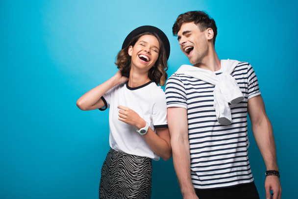 happy, trendy man and woman laughing together on blue background - Valokuva, kuva