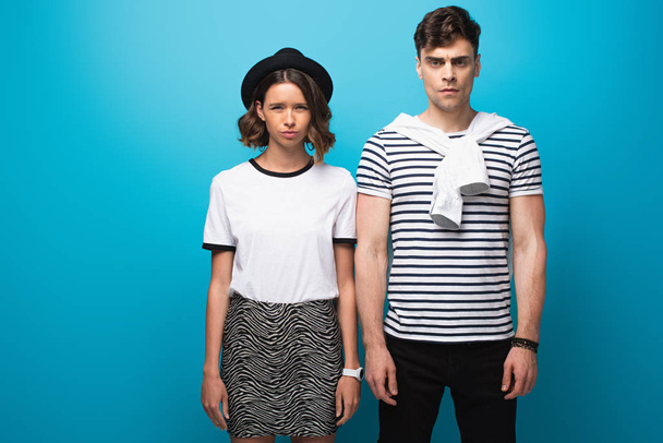 displeased, trendy man and woman looking at camera on blue background - Foto, Imagem