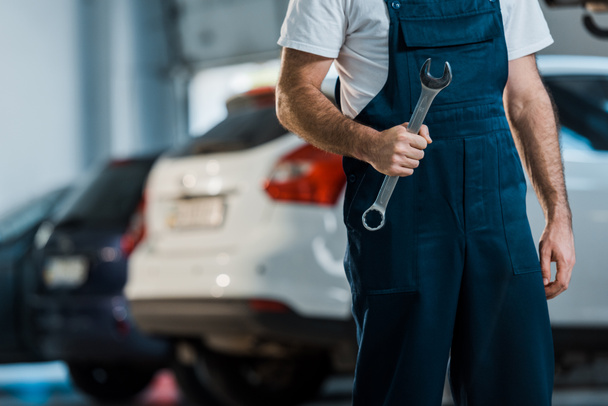 cropped view of car mechanic holding hand wrench in car service  - Foto, afbeelding