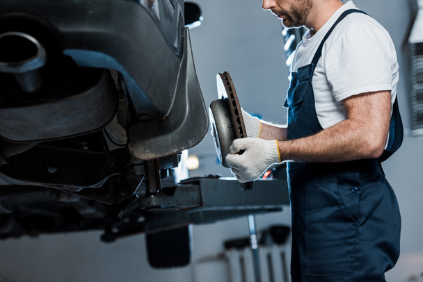 cropped view of auto mechanic repairing automobile and holding car brake - Photo, Image