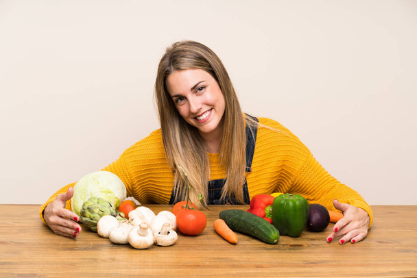 Mulher loira feliz com lotes de legumes
 - Foto, Imagem