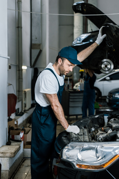 araba motoru bakarak eldiven yakışıklı sakallı oto tamircisi  - Fotoğraf, Görsel