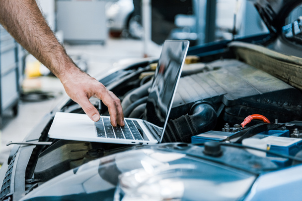 cropped view of auto mechanic using laptop with blank screen near car  - Photo, Image