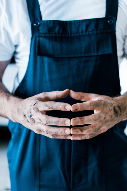 Ausgeschnittene Ansicht eines Werkstattmitarbeiters, der mit geballten Händen steht  - Foto, Bild