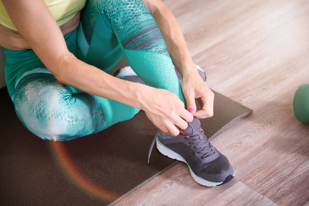 Sport. Žena v posilovně dělá strečink cvičení a usmívá se na podlaze - Fotografie, Obrázek