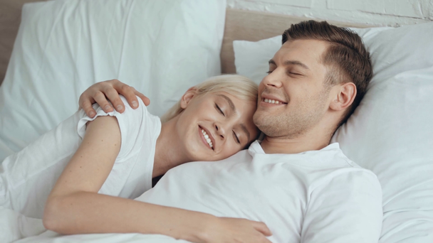 bela mulher falando e abraçando o homem sorridente na cama
 - Filmagem, Vídeo