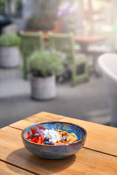 Morning Breakfast in a blue plate on the table. fresh berries Blueberry smoothie breakfast bowls of nuts, seeds and fruit. selective focus. - Foto, Imagem