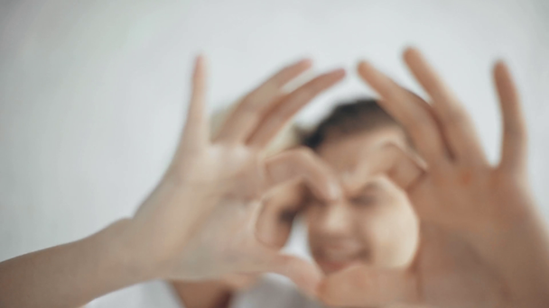 вибірковий фокус красивої усміхненої пари, яка дивиться на камеру, показує символ серця і цілується вдома
 - Кадри, відео
