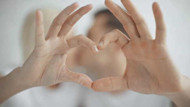pareja besando y mostrando el símbolo del corazón con las manos
 - Imágenes, Vídeo