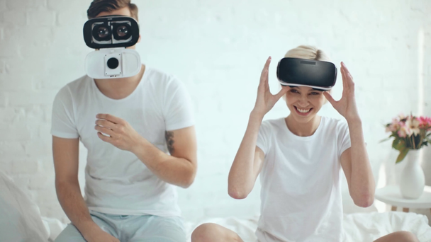 Nainen katselee miestä virtuaalitodellisuus kuulokkeet ja nauraa kotona
 - Materiaali, video