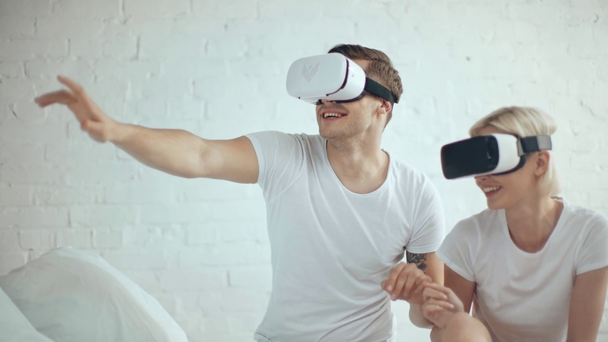excited couple in Virtual reality headsets smiling and gesturing at home - Filmmaterial, Video