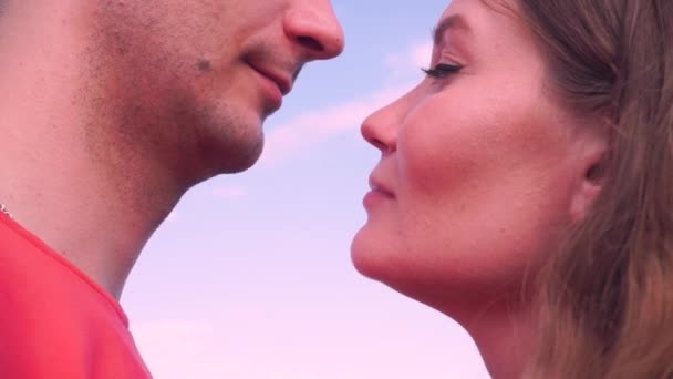 bliska, młody mężczyzna i kobieta całują się delikatnie przed niebem - Materiał filmowy, wideo