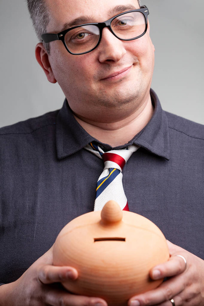 Усміхнений чоловік тримає керамічну грошову коробку
 - Фото, зображення