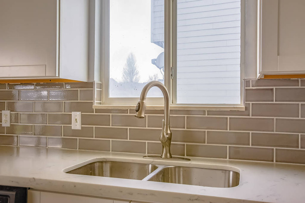 Double évier et robinet d'une cuisine avec vue sur l'extérieur par la fenêtre
 - Photo, image