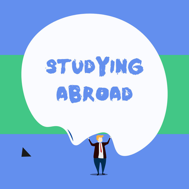 Text sign showing Studying Abroad. Conceptual photo learn outside of home in foreign country Travelling Front view standing man dressed suit tie two hands up big deflated balloon. - Photo, Image