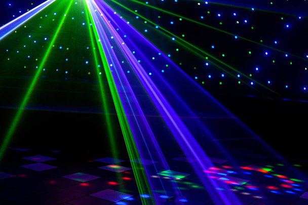 helle Nachtclub-Laserlichter, die sich durch den Rauch der Rauchmaschine schneiden und Licht und Regenbogenmuster auf der Tanzfläche erzeugen. Laserlichter mit Bokeh im Hintergrund. Inspiration für Mardi Gras oder Nightlcub Promotions. - Foto, Bild