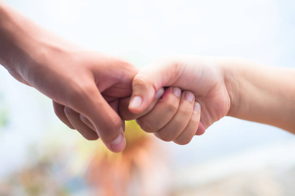 Close up shot of two hands one of father and daughter with blurred background. Concept of Father's day and taking care of female child. Helping to conquer fear and obstacles in practical life. - 写真・画像