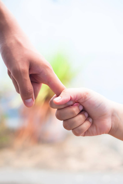 Hand of female child holding the hand of matured man, Shot with blurred background. Concept of Father's day. Men helping the female hand to overcome conquer obstacles and fears. Vertical shot. - Photo, image