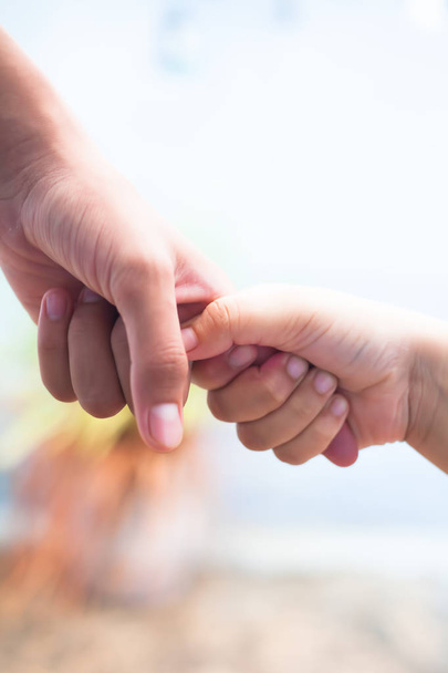 Hand of female child holding the hand of matured man, Shot with blurred background. Concept of Father's day. Men helping the female hand to overcome conquer obstacles and fears. Vertical shot. - 写真・画像
