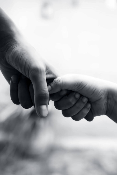Hand of female child holding the hand of matured man, Shot with blurred background. Concept of Father's day. Men helping the female hand to overcome conquer obstacles and fears. Vertical shot. - Photo, Image
