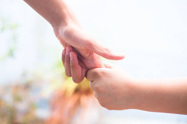 Female child's hand holding the hand of elder male shot with bokeh background and horizontal. Concept of father's day ( 16th June).  - Foto, imagen