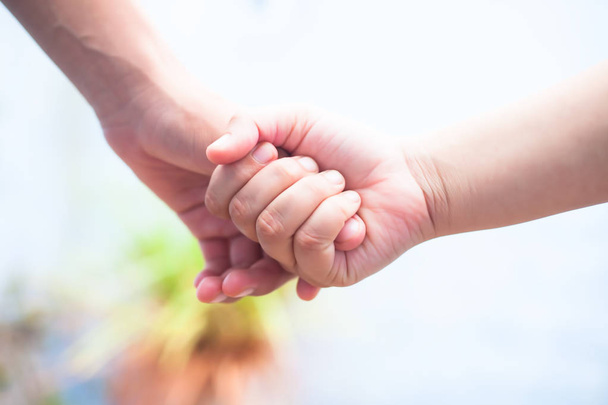 Female child's hand holding the hand of elder male shot with bokeh background and horizontal. Concept of father's day ( 16th June). - Foto, imagen