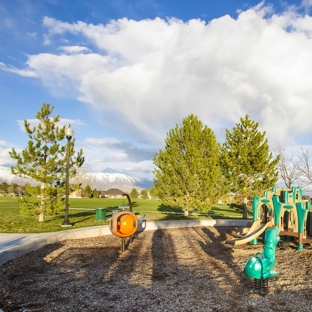 Τετράγωνο πλαίσιο παιδική χαρά στη μέση ενός κυκλικού μονοπατιού και αχανές χωράφι με δέντρα - Φωτογραφία, εικόνα