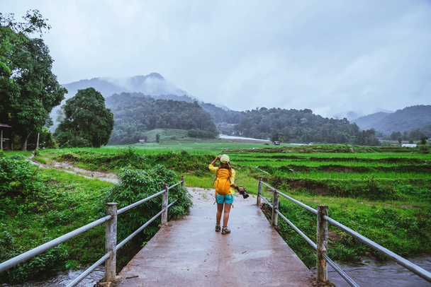 Las mujeres asiáticas viajan naturaleza. Caminar una foto del campo de arroz y detener tomar un descanso relajarse en el puente en ban Mae klang luang en temporada de lluvias
. - Foto, imagen