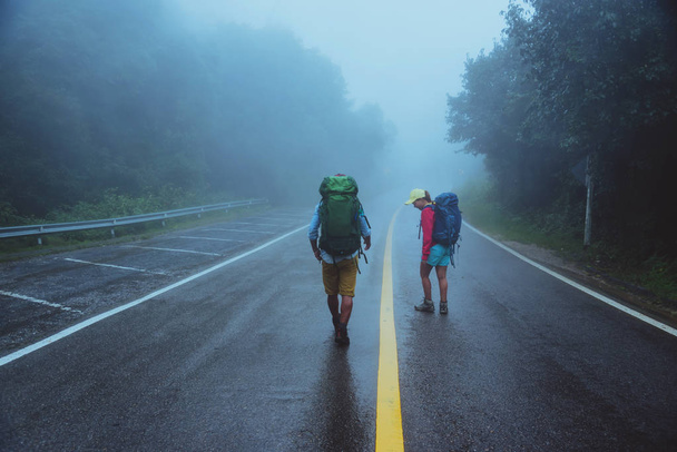 恋人アジアの男性とアジアの女性は、自然を旅行します。道路ルートを歩く。幸せに自然を旅する。霧雨の中梅雨の季節に. - 写真・画像