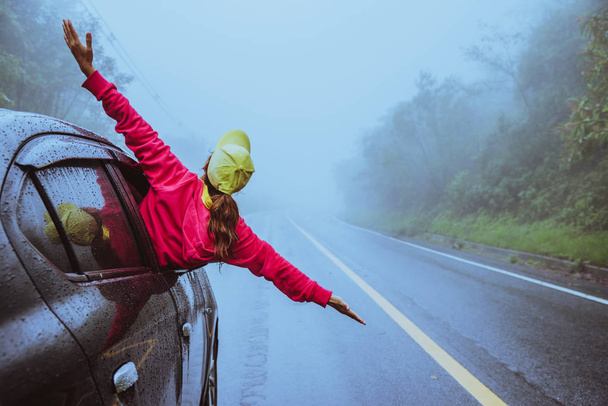 asiatische Frauen reisen entspannt in den Urlaub. glücklich Auto fahren. inmitten des Nebels regnerisch. - Foto, Bild