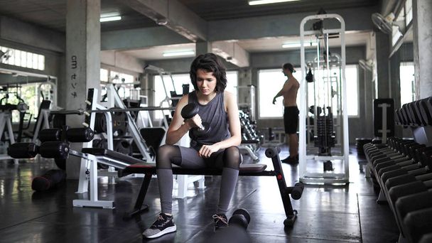 Sportos fiatal nők gyakorlása által emelő súlyzók az edzőteremben, társ - Fotó, kép